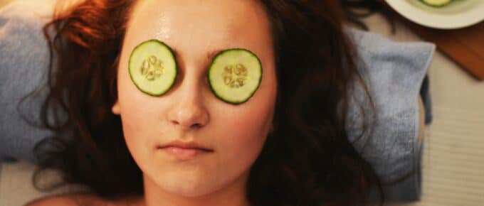 woman practicing self care with cucumbers on her eyes